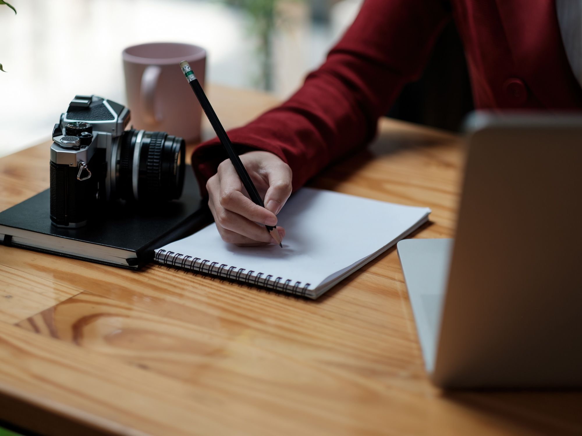 Person writing in notebook while reading from a computer